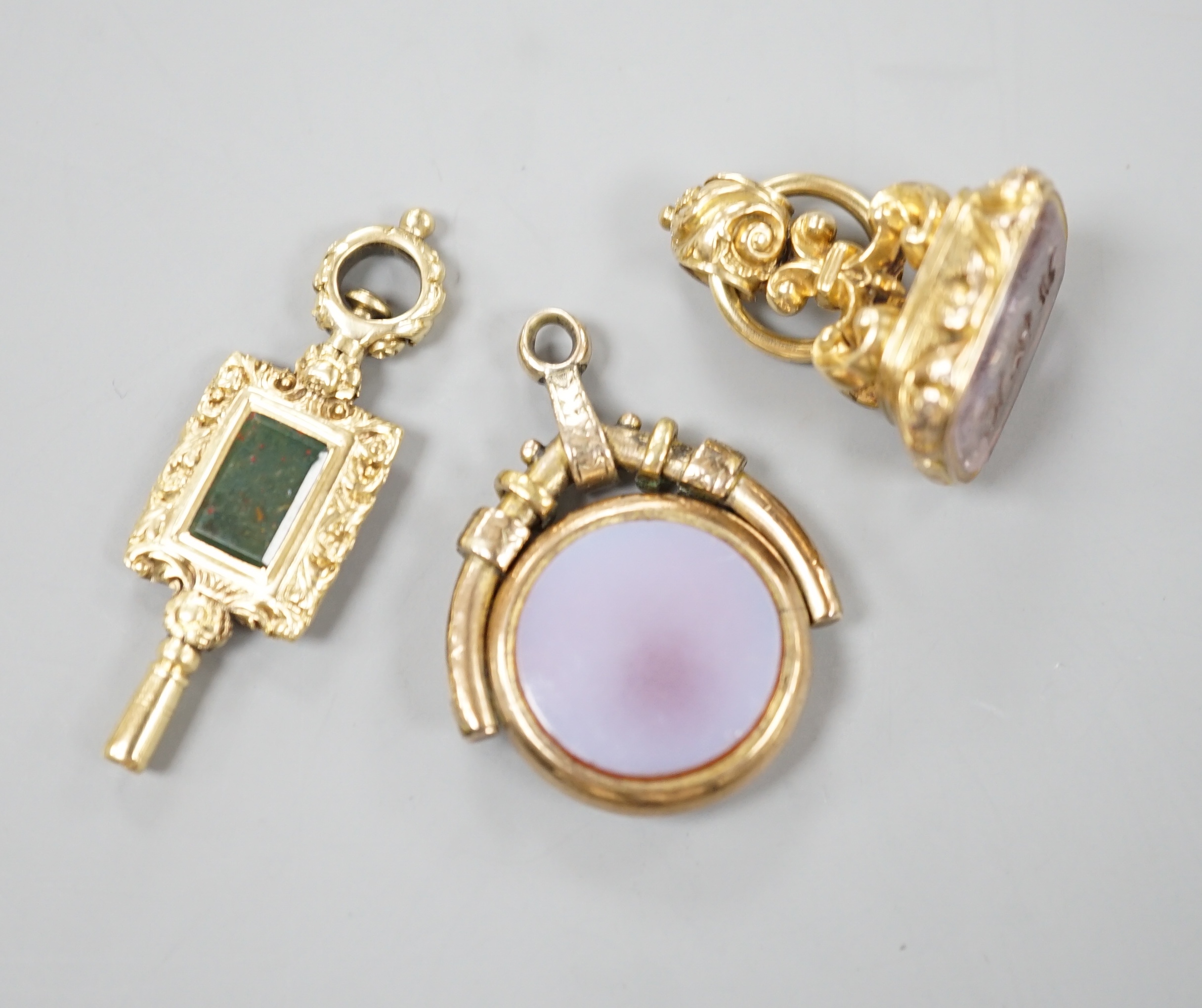 A 19th century yellow metal overlaid and foil backed gem set fob seal, 25mm, a similar chalcedony set spinning fob and a bloodstone set yellow metal overlaid watch key.